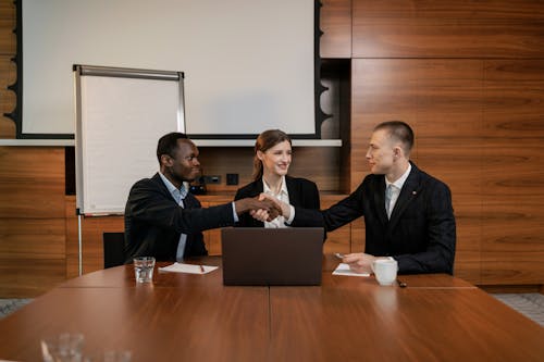 A Woman Sitting Between Two Men Doing Handshake