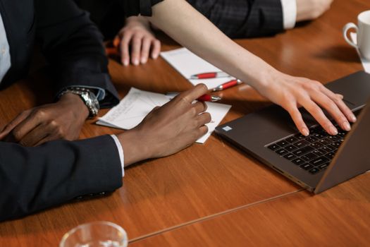 Professionals collaborating over a laptop in a business meeting setting indoors.