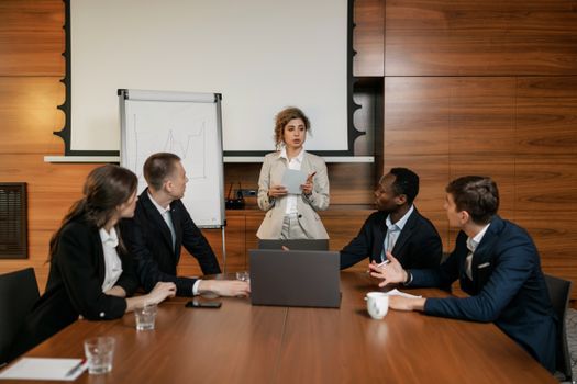 Business team in a modern office discussing a presentation with diverse group dynamics.