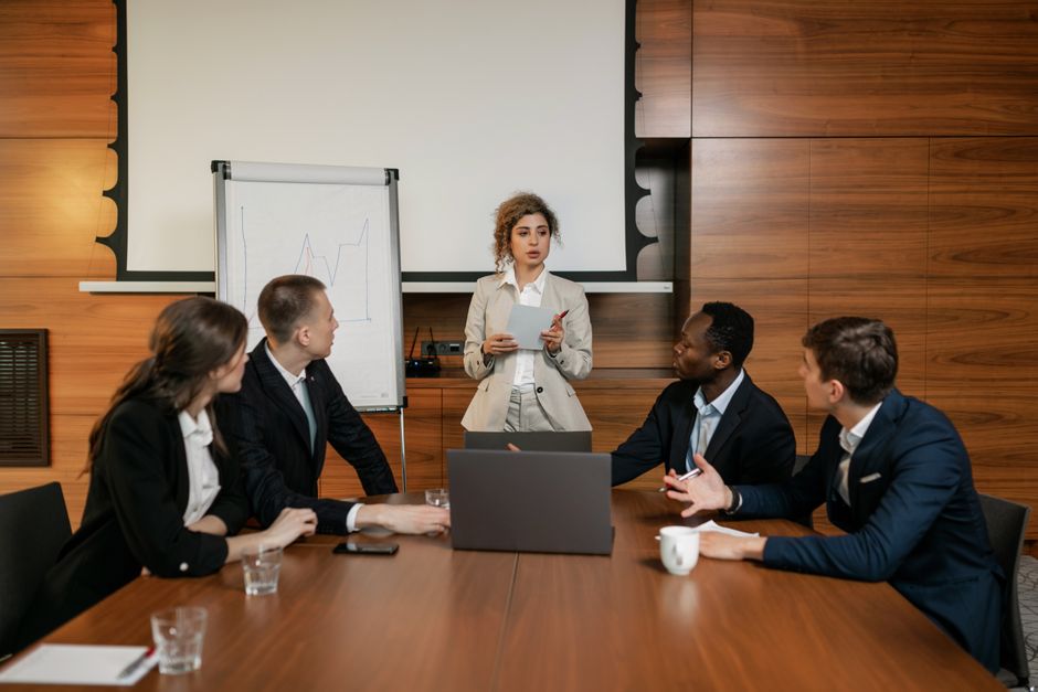 Equipe de negócios em um escritório moderno discutindo uma apresentação com dinâmicas de grupo diversificadas.