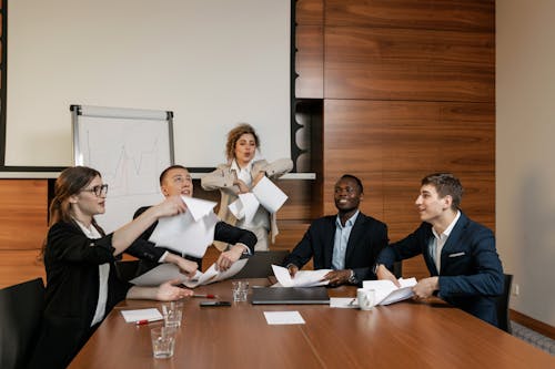 Free Woman in Gray Blazer Holding Paper Having Fun with Her Colleagues Stock Photo