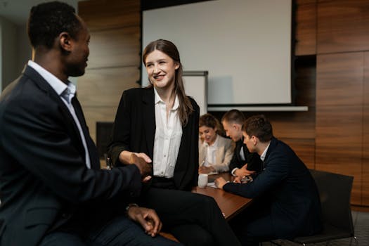 Colleagues shaking hands during a professional team meeting in an office setting.