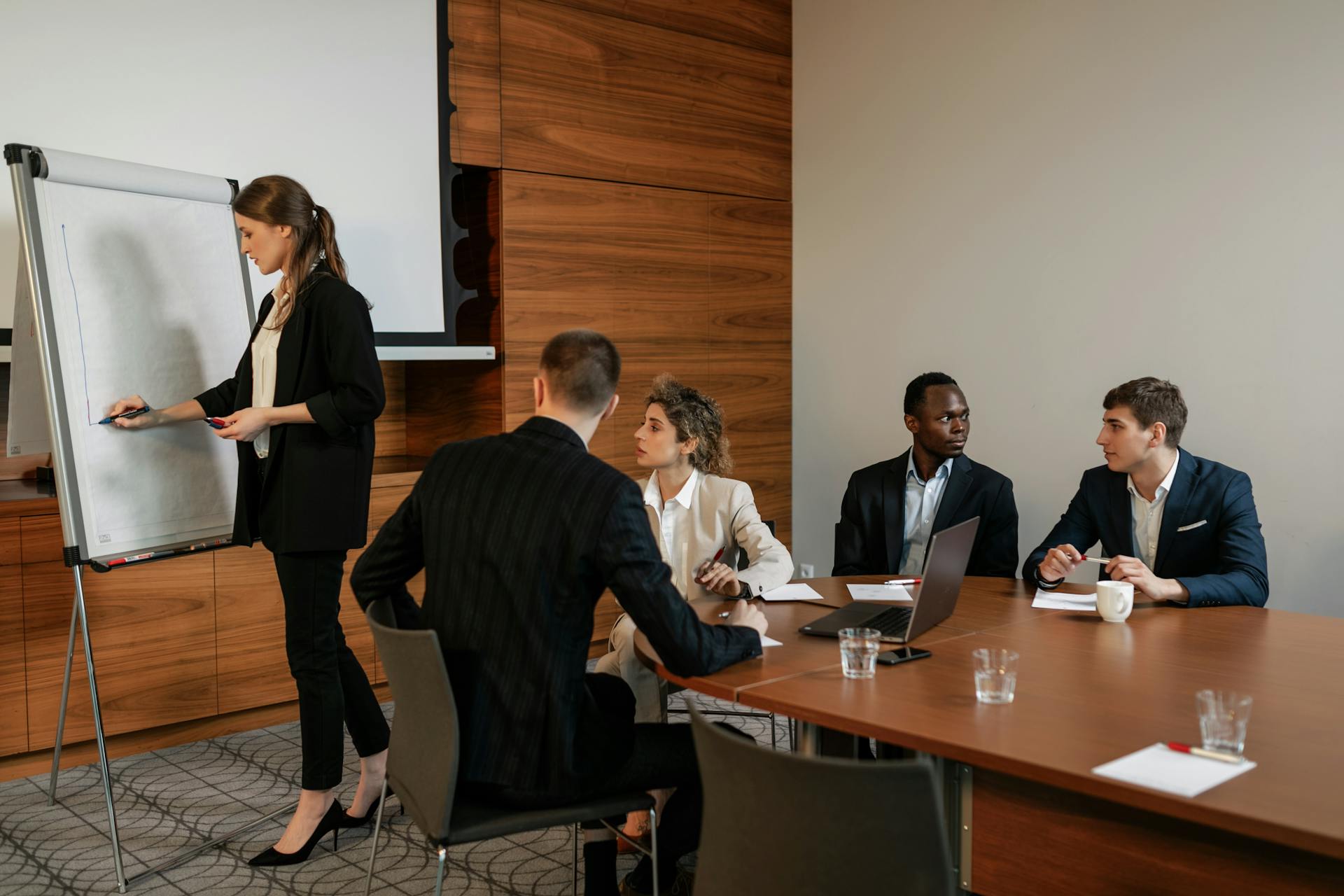 A diverse group of professionals in a business meeting discussing a presentation indoors.