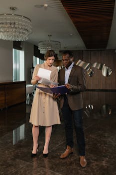 Two professionals discussing documents in a stylish office environment, exhibiting teamwork.