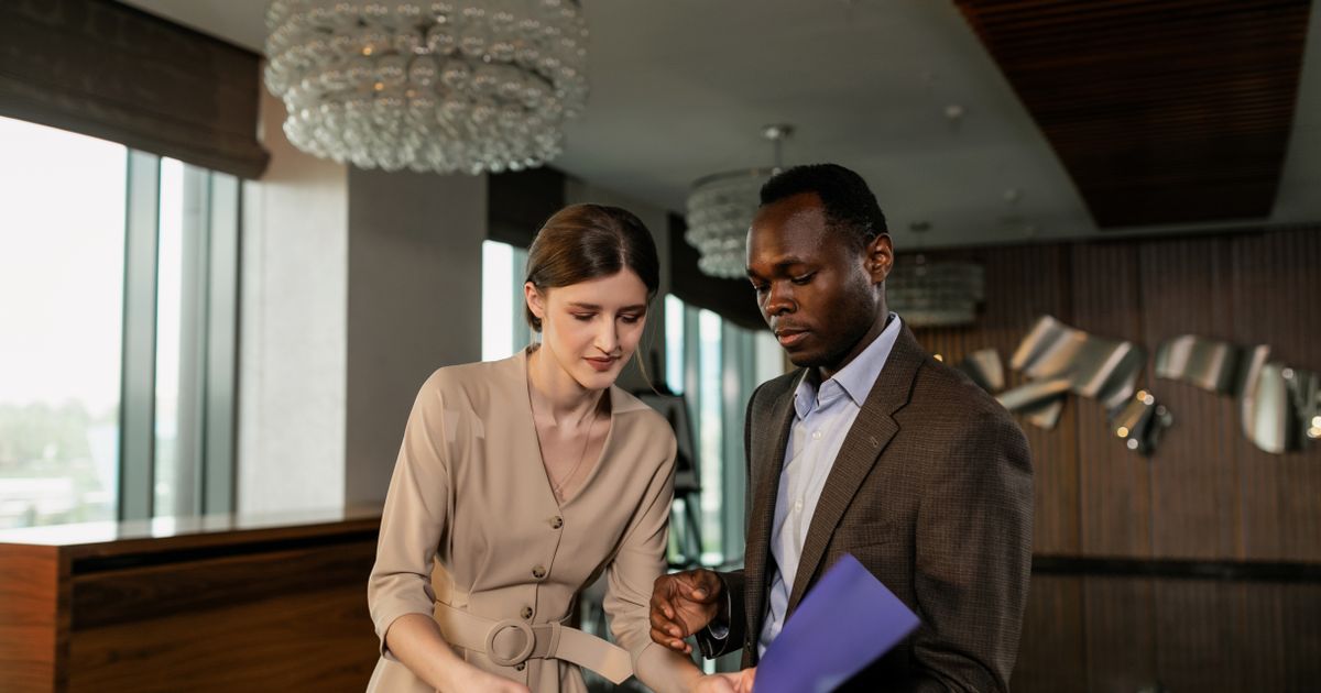 Two professionals reviewing printed documents during a business meeting in a modern office