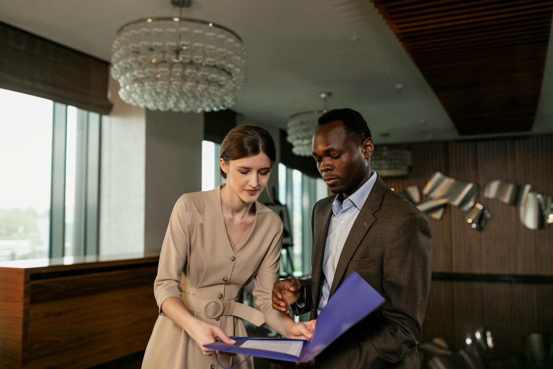 Two professionals reviewing documents during a business meeting in a modern office setting.