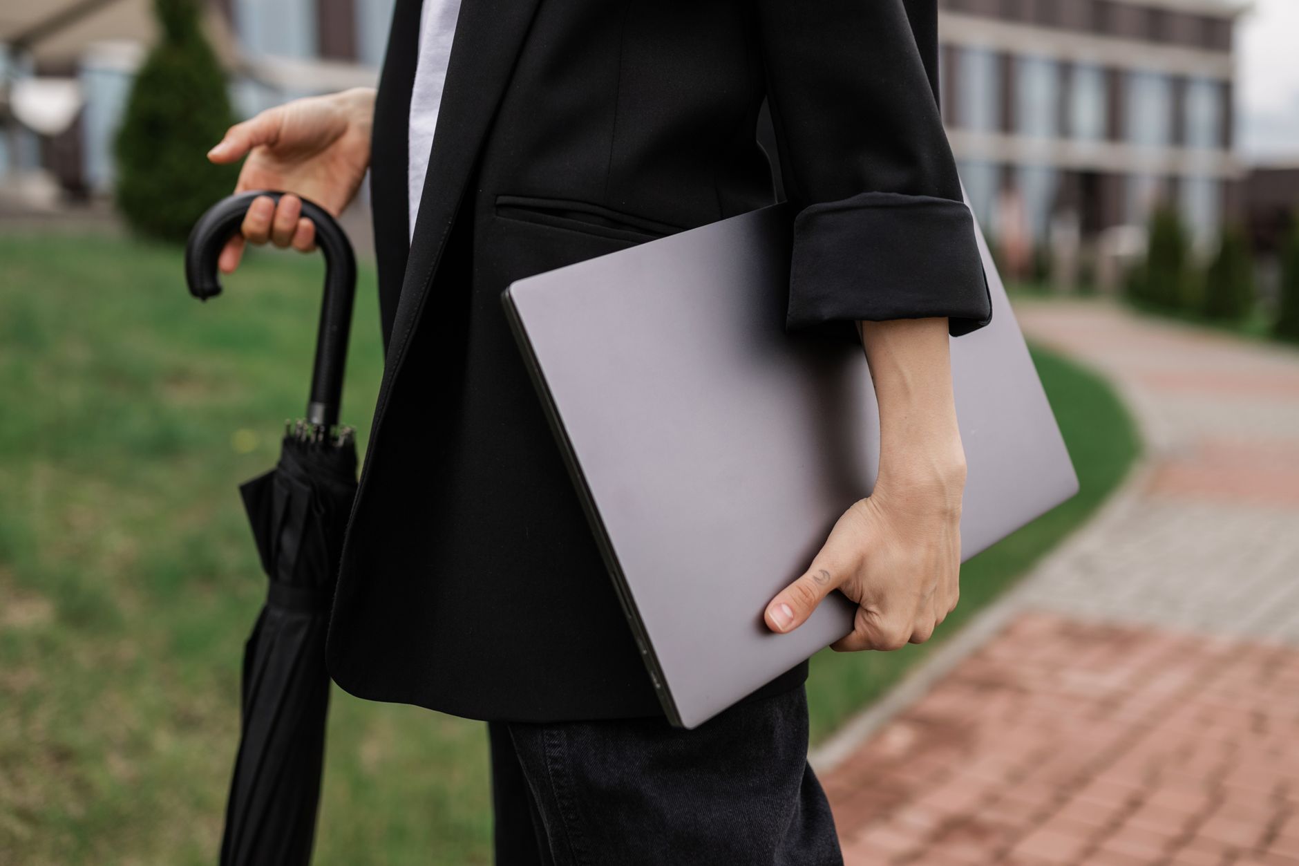 Close-up of a person holding a laptop and an umbrella, signifying business mobility outdoors.