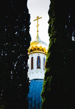 透过树木瞥见的东正教教堂，金色圆顶和十字架凸显了其灵性与建筑之美