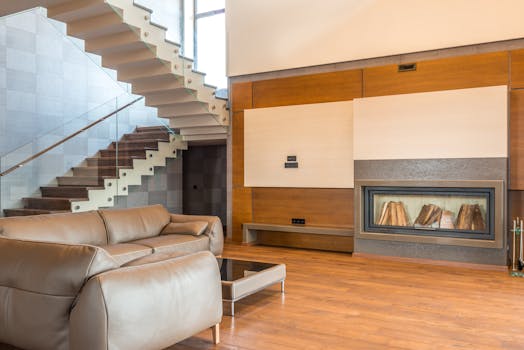 Modern living room featuring a minimalist design with a sleek staircase and comfortable leather sofa.