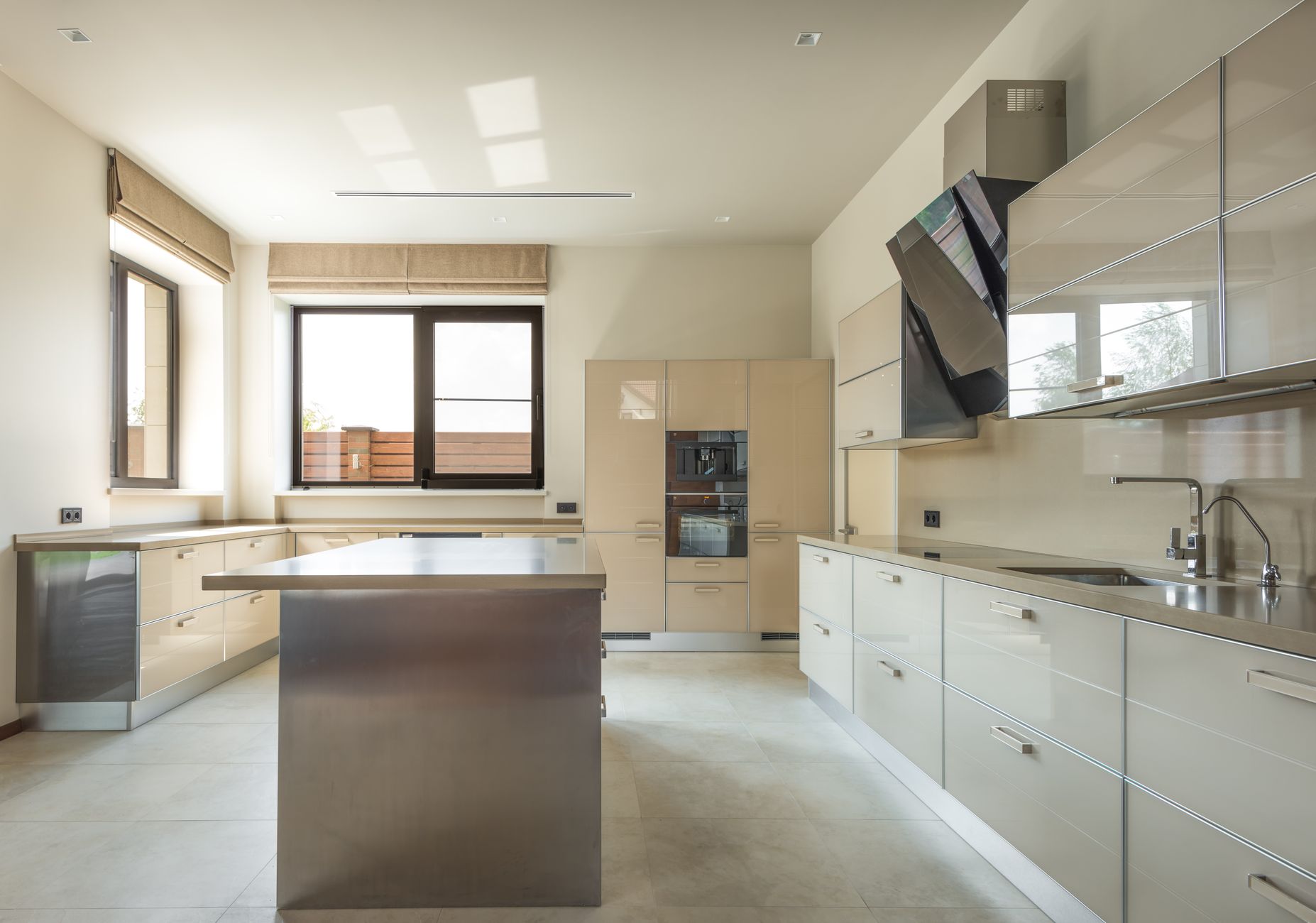A bright luxury kitchen featuring mushroom gray cabinets with matte finish, quartz countertops, and brass hardware under warm pendant lighting