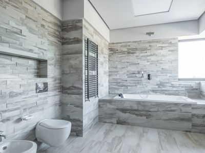 Spacious modern bathroom with bathtub and stone tiles