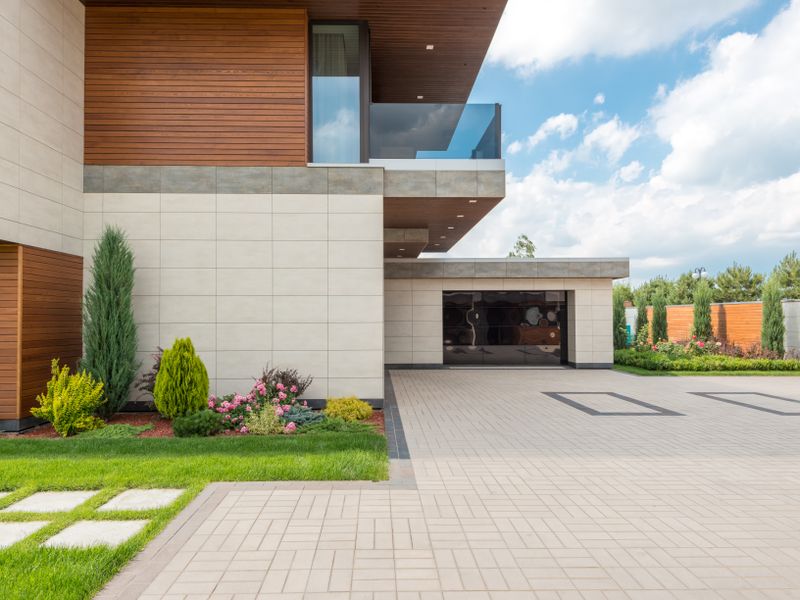 Modern house with a spacious driveway and landscaped garden under a clear sky