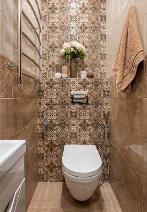 Free White Ceramic Toilet Bowl in Brown Tiled-Wall Water Closet Stock Photo