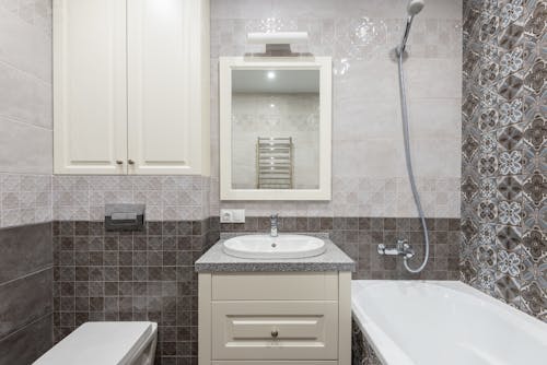 Free A White Ceramic Sink Near the Bathtub with Shower Head Stock Photo