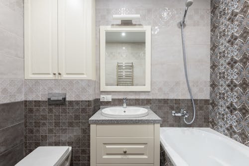 A White Ceramic Sink Near the Bathtub with Shower Head