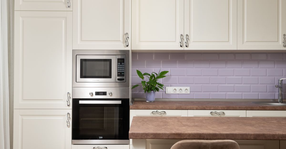 Interior de cozinha estiloso com armários, micro-ondas embutido e decoração elegante.