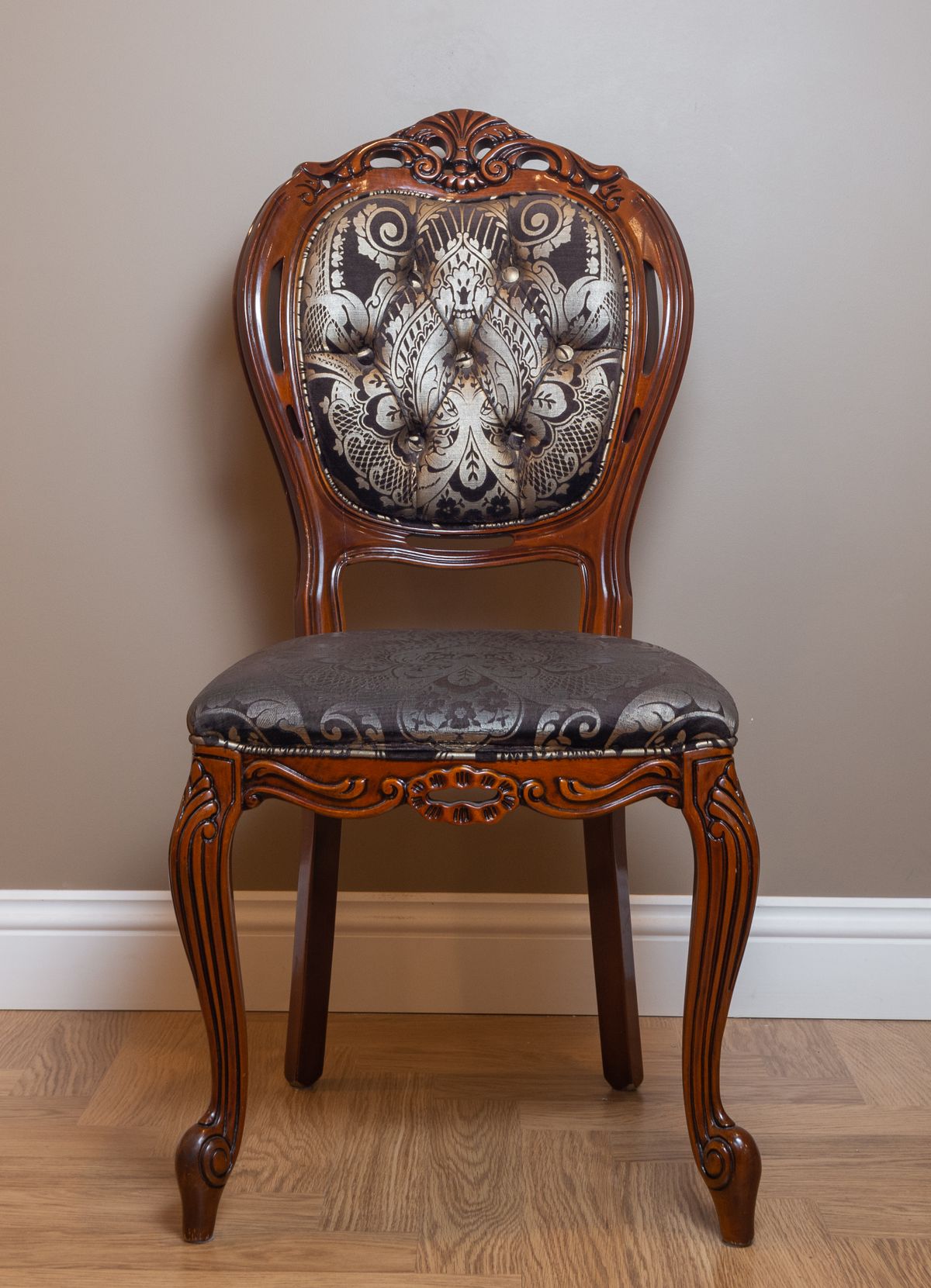 Carved walnut fauteuil with damask upholstery against a neutral wall