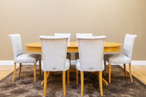 A Wooden Table with Chairs on a Dining Area with Brown Carpet on a Wooden Floor