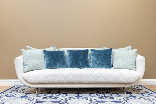 Бесплатное стоковое фото с Бежевая стена, диван, диванные подушки