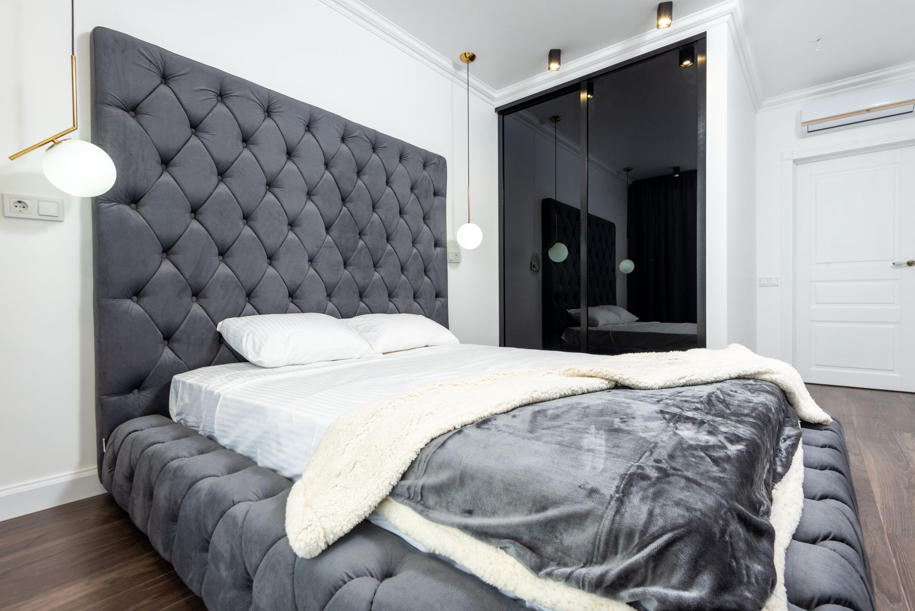 Plush grey upholstered headboard with a matching grey comforter and soft bedroom furnishings