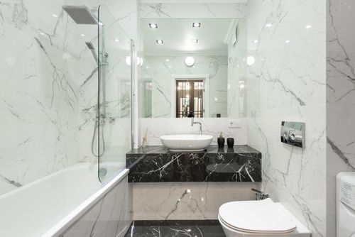 Free Elegant bathroom with marble decor, featuring bathtub, washbasin, and modern fixtures. Stock Photo