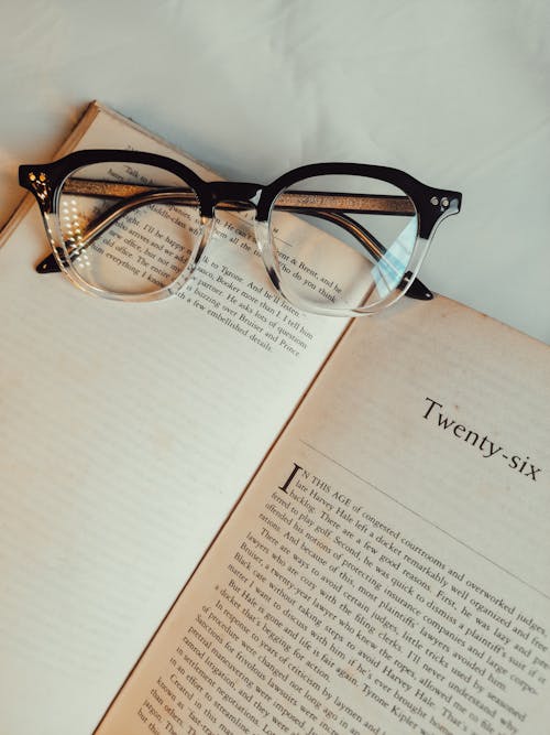 Free Overhead Shot of Black Framed Eyeglasses on Top of a Book Stock Photo