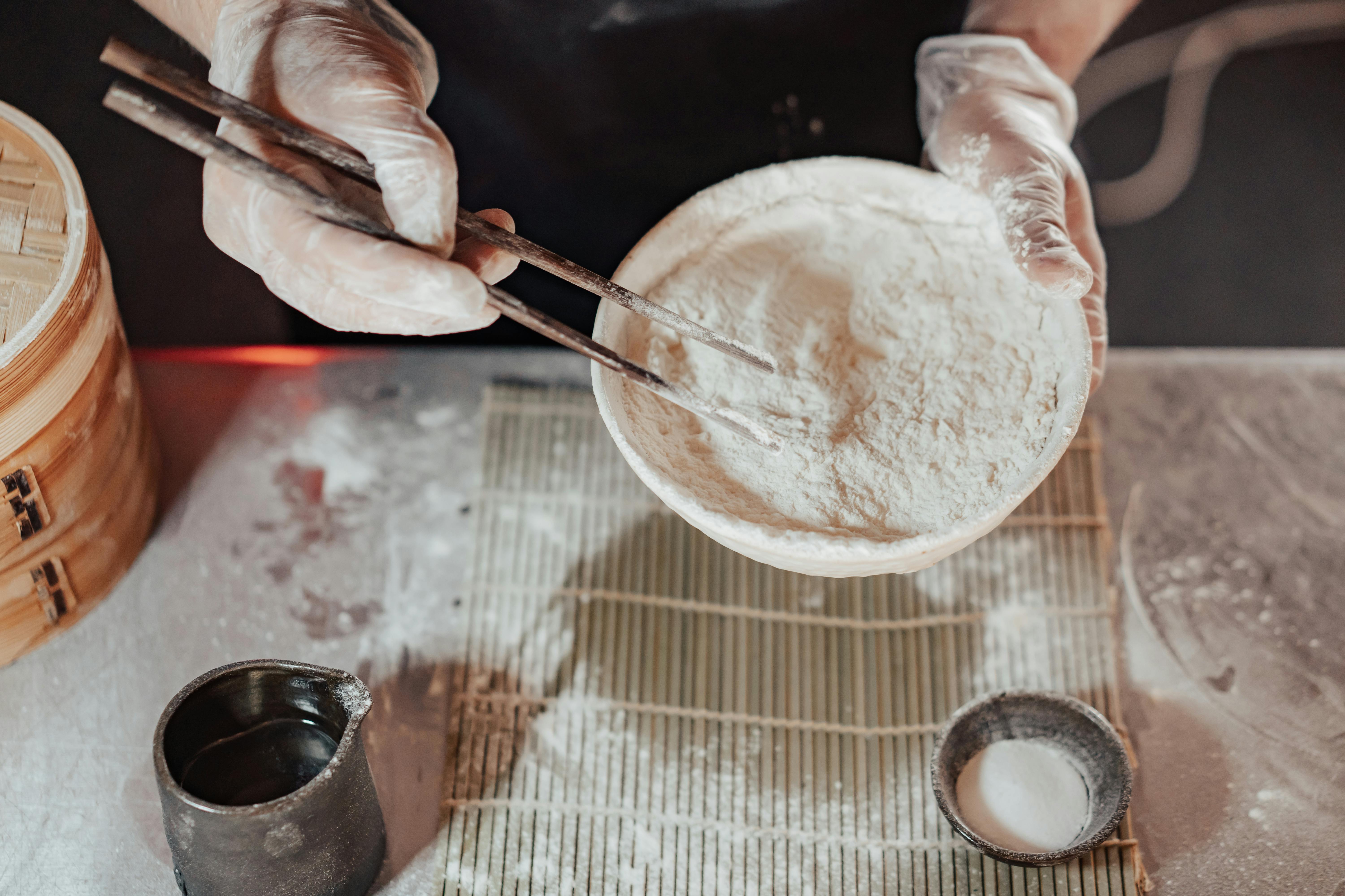 a person wearing latex gloves while holding a bowl of flour