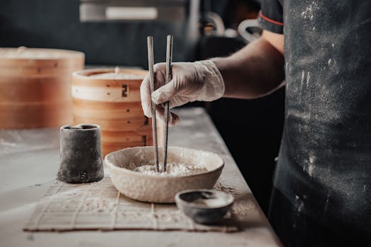 Close-up of a Japanese chef using chopsticks to delicately prepare rice in a culinary setting.