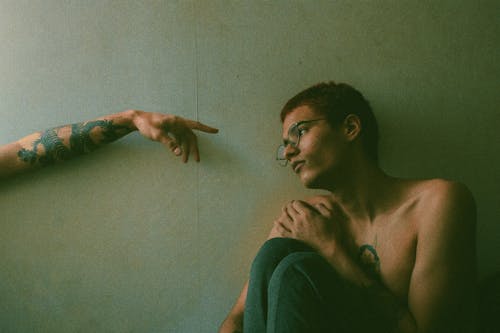 Photo of a Hand Reaching for a Shirtless Man
