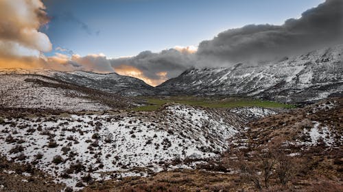 Fotografía Escénica De Montañas Cubiertas De Nieve Bajo Un Cielo Nublado