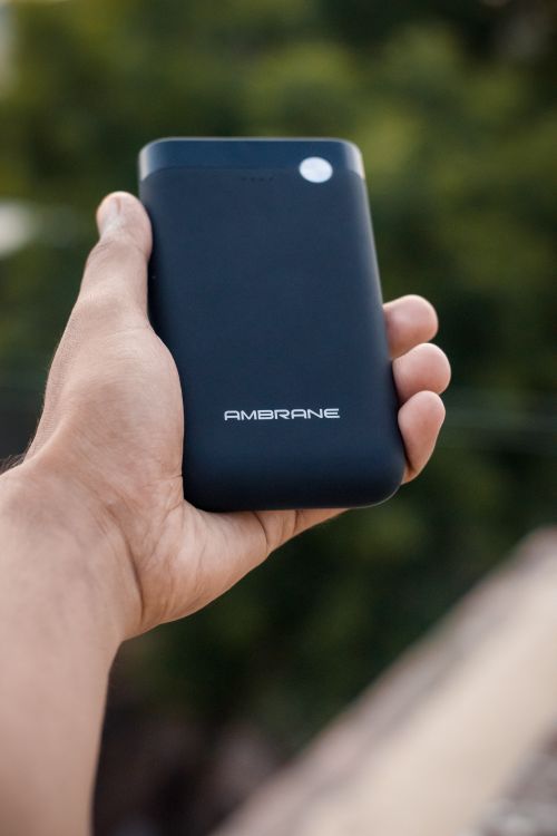 Hand holding a black power bank outdoors, illustrating everyday portable use