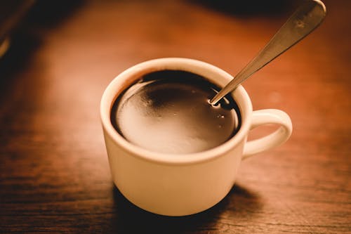 無料 茶色の木製の表面にコーヒーで満たされた白いセラミックエスプレッソカップ 写真素材