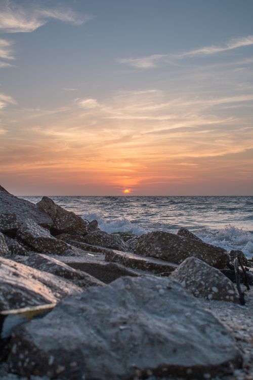 Free A breathtaking sunset over a rocky seashore with vibrant sky colors and ocean waves. Stock Photo