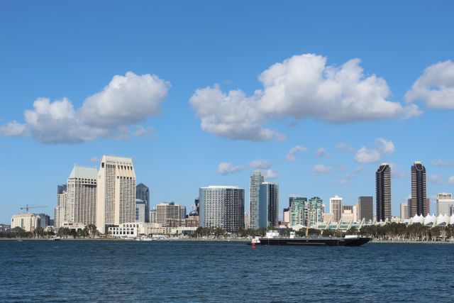 View of San Diego skyline with tall buildings and a ship on a bright day.