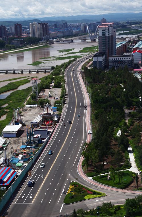 Free Aerial shot of a city road with moving cars, green areas, and skyline. Stock Photo