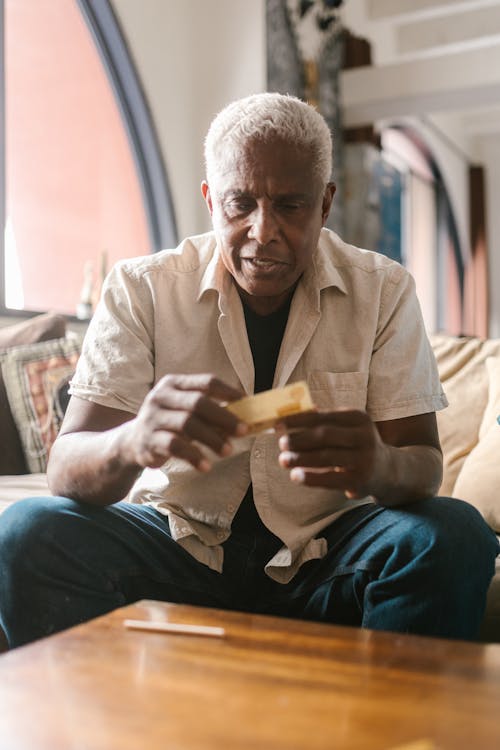 An Elderly Man Holding a Pack of Rolling Papers