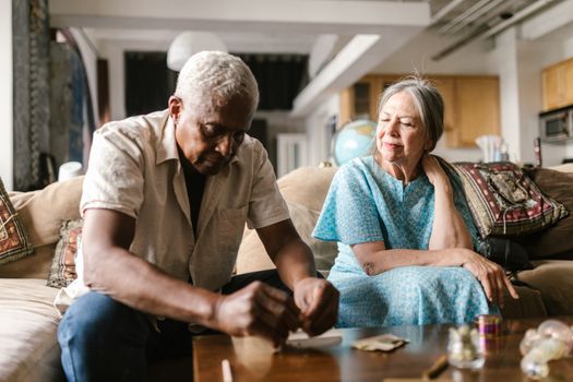 A senior couple engaging in a relaxed indoor activity, sitting on a couch in a cozy home setting.