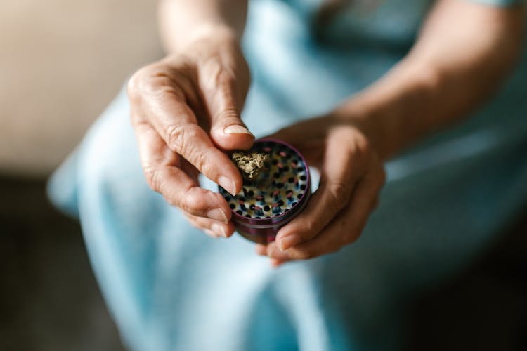 A Person Holding A Weed Grinder With Marijuana