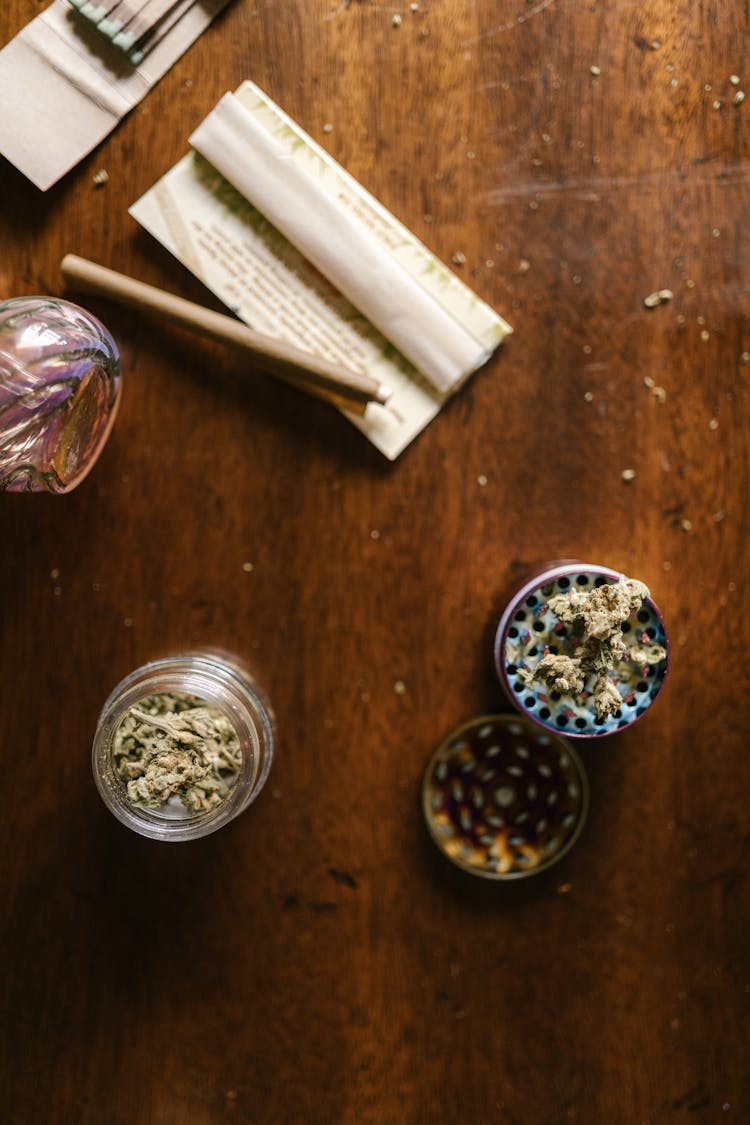 A Weed Grinder And A Roll On A Wooden Table