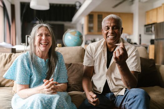 Elderly couple enjoying a relaxed afternoon indoors, smiling together.