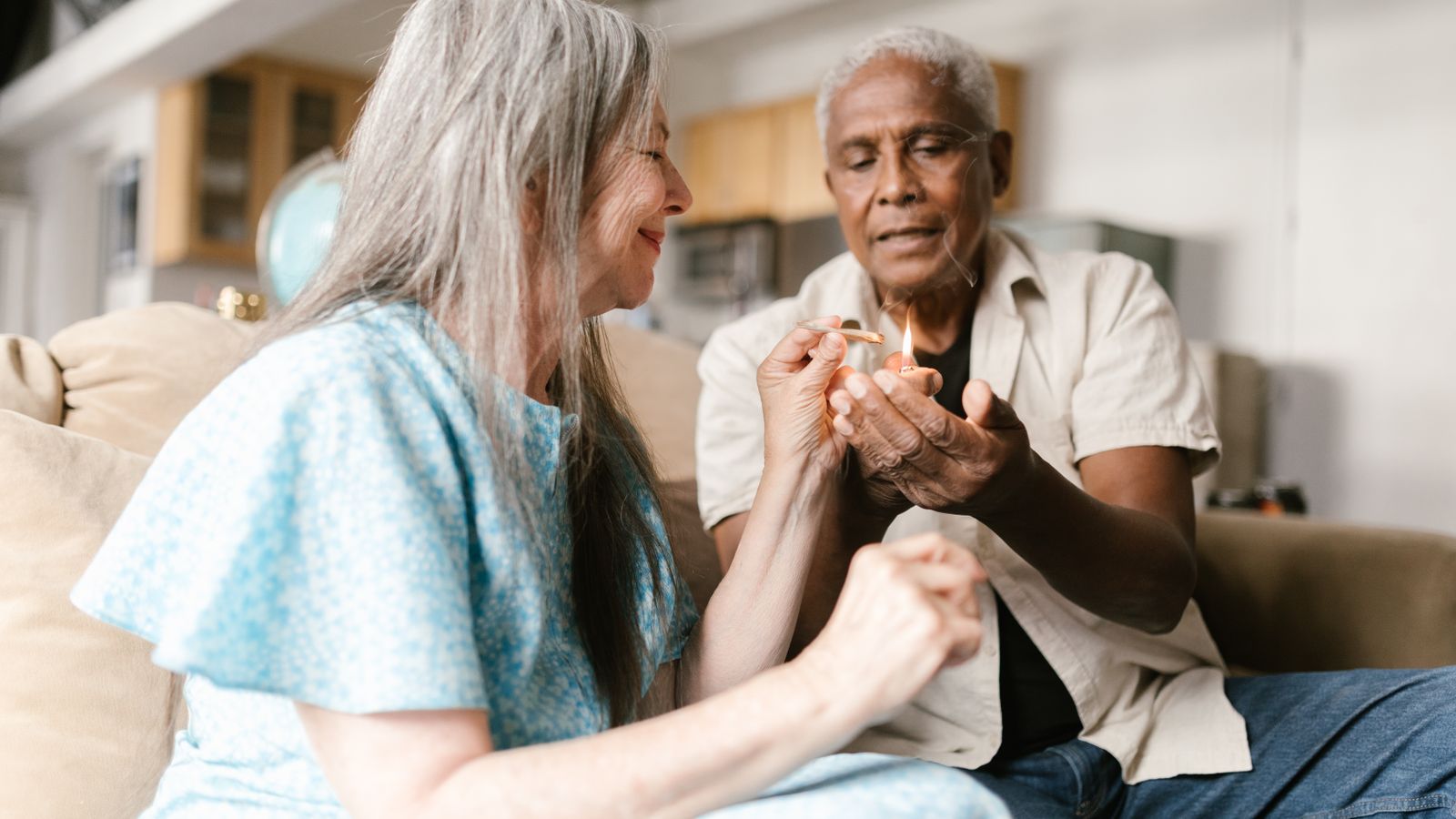 An elderly couple enjoys cannabis together in a cozy indoor setting.