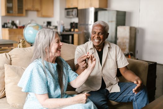 Happy senior couple sharing a moment, smoking a joint in cozy indoor setting.