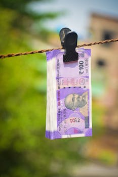 Close-up of Indian 100 rupee notes clipped on a rope outdoors in Kolkata.