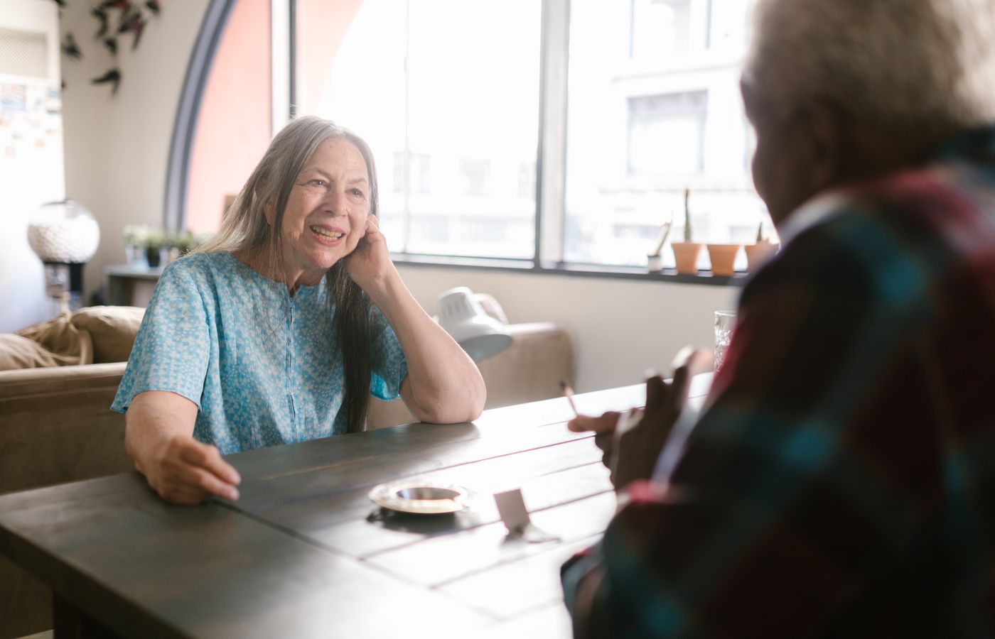 Elderly woman smiling in a cozy indoor setting, enjoying a conversation.