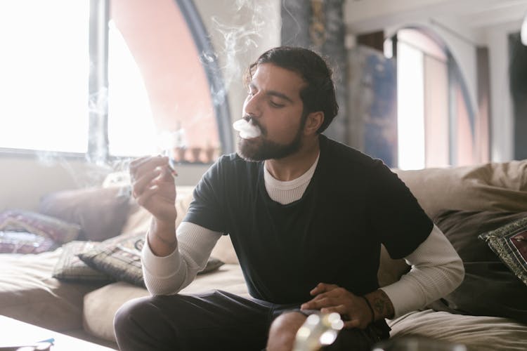 A Man In Black Shirt And White Sweatshirt Smoking Weed