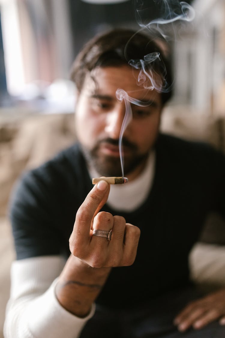 A Man Holding A Joint With Smoke