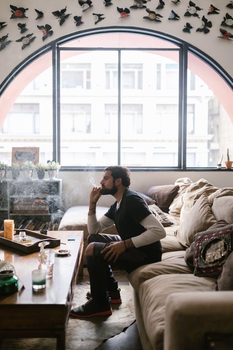 A Man Sitting On The Couch While Smoking Weed