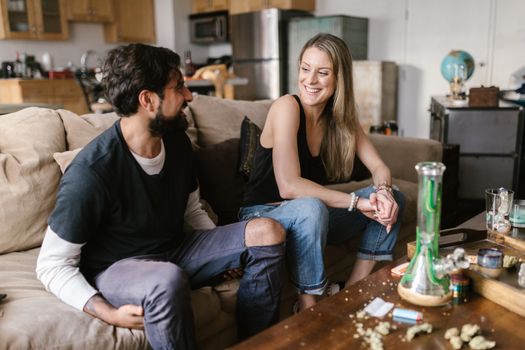 Two friends enjoy a relaxed conversation with cannabis in a comfortable home setting.