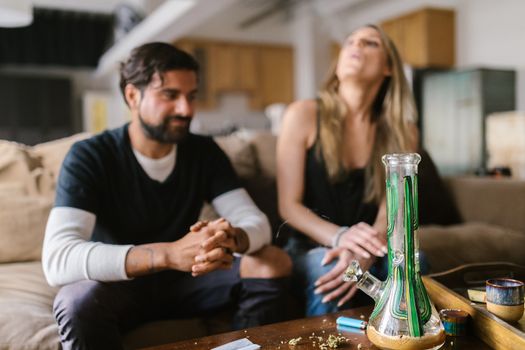 Adults enjoying a relaxed moment indoors with cannabis paraphernalia on the table.