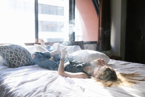 Free Woman Lying on the Bed While Smoking  Stock Photo
